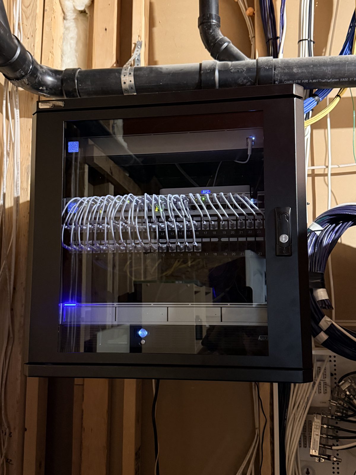 Finished HPSI wall-mount network rack with uniformly dressed white patch cables behind a locked glass door